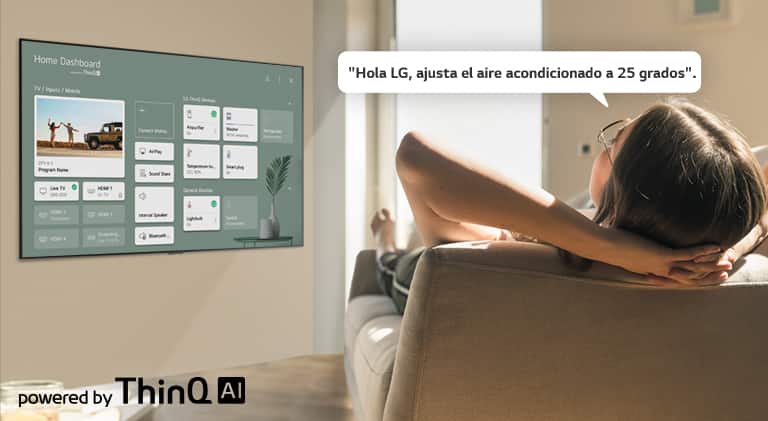 Mujer recostada en un sofá diciéndole a la TV que baje la temperatura con el Panel de inicio en la pantalla de la TV.