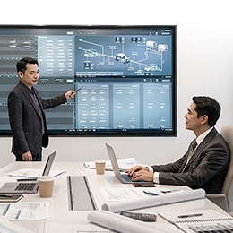 Satisfied, looking consultants are examining the blueprint while wearing safety helmets.