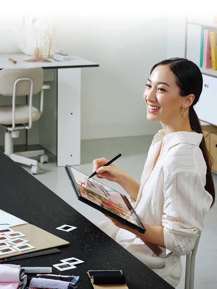 Woman using LG Gram Pro 2-in-1 in tablet mode with pen.