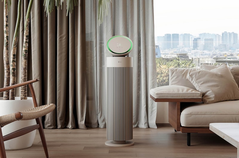 LG air purifier placed in a stylish living room with a beige sofa, dark bookshelf, and modern décor