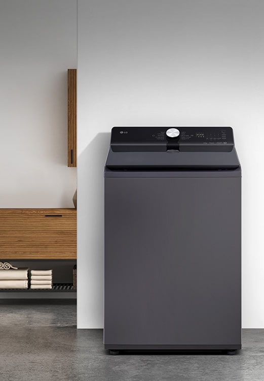 Dark gray LG top-load washing machine with sleek, modern design placed in a minimalist laundry space