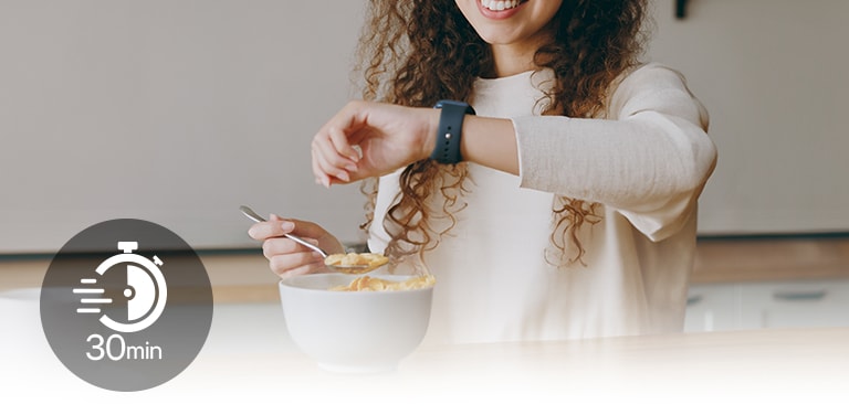 Woman at a table glancing at her wristwatch during a light meal, with a '30 min' icon overlayed on screen