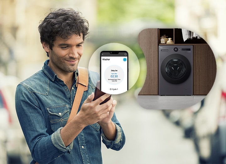 The man is looking at the smartphone and is showing the screen and washing machine image of the smartphone next to him
