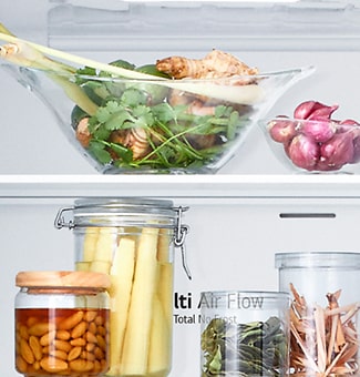 Close up view of lg bottom freezer refrigerator shelf with various fresh herbs, vegetables, and preserved foods in glass containers.