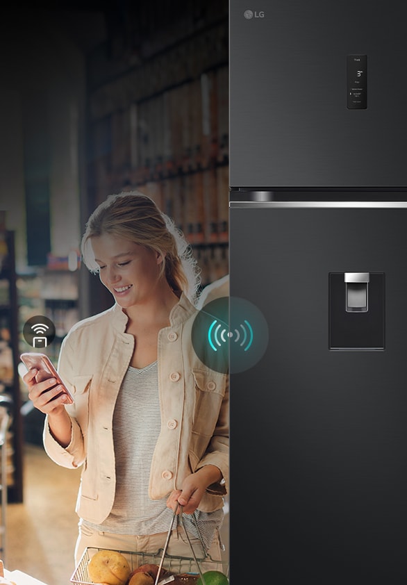A woman controlling an lg refrigerator remotely using her smartphone. The image highlights the refrigerator's smart connectivity, allowing users to manage and adjust settings from their mobile device.