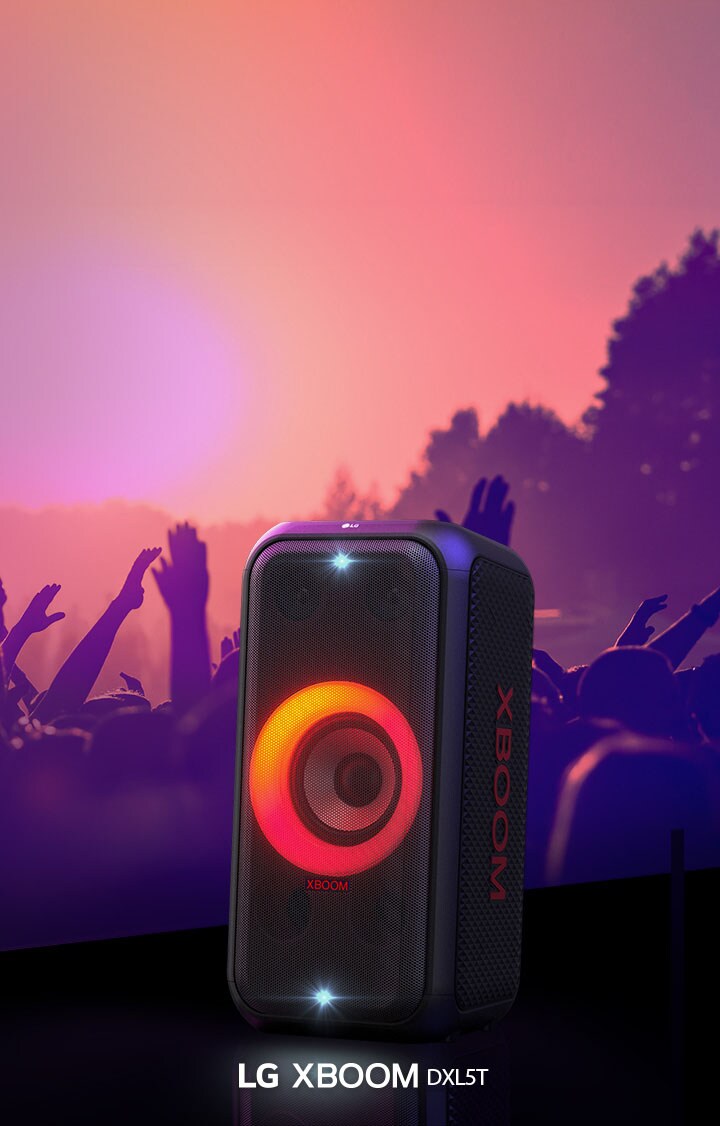 LG XBOOM XL5S is placed on the stage with red-orange gradient lighting is on. Behind the stage, people enjoy the music.