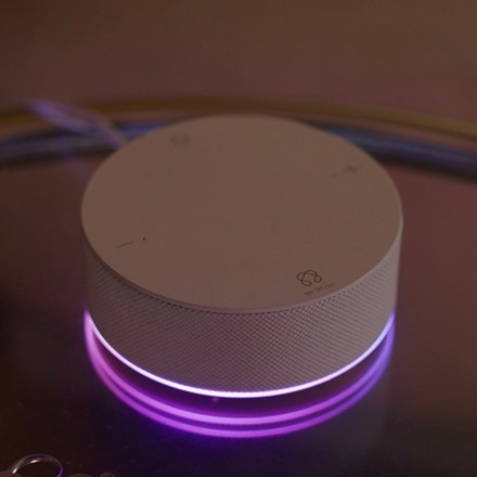 Biały produkt ThinQ ON na stole emituje fioletowe światło.  