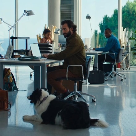 Mężczyzna i jego pies siedzą przy biurku w biurze, tworząc ciepłą i przyjazną atmosferę pracy.  