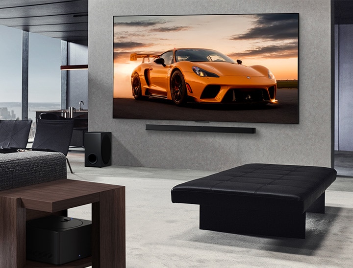 Przestronny salon z widokiem na panoramę miasta. LG OLED TV zamontowany na ścianie z LG Soundbar. Widoczna jest ultrasmukła konstrukcja telewizora. Zero Connect Box jest dyskretnie ukryty i praktycznie niewidoczny.