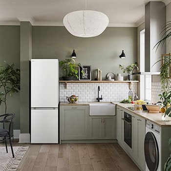 Lodówko-zamrażarka LG GBV3100CSW w kolorze białym, wkomponowana w nowoczesną, zieloną kuchnię, podkreśla elegancki i płaski design drzwi.