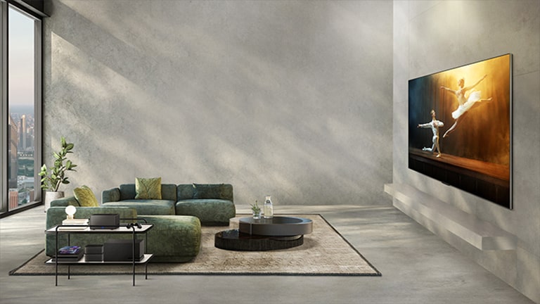 Film przedstawiający telewizor LG OLED M3 na szarej ścianie w nowoczesnym salonie, z występem baletowym odtwarzanym na ekranie. Do telewizora podłączone są nieuporządkowane kable, systemy dźwiękowe i konsole do gier. Następnie wszystkie urządzenia peryferyjne znikają, a na bocznym stoliku w pokoju pojawia się moduł Zero Connect, zapewniając niezakłócony widok na ekran.