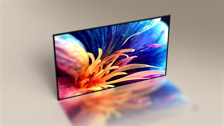 Super smukły LG TV z perspektywy lotu ptaka. Kąt kamery przesuwa się, aby pokazać przednią stronę telewizora, wyświetlając powiększony obraz kolorowego kwiatu.
