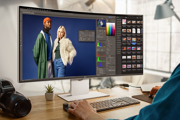 Mężczyzna pracuje z programem do projektowania na monitorze UltraFine. Obok monitora umieszczona jest kamera.