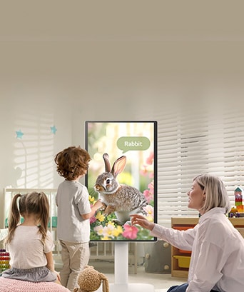 Zdjęcie przedstawia kobietę i trójkę dzieci bawiących się na monitorze LG Smart Monitor Swing.