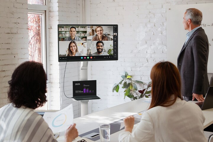 Zespół w sali konferencyjnej korzystający z monitora LG Smart Monitor Swing ze stojakiem Swing Stand i nakładką Swing Stand Plate, na której umieszczono laptop LG gram, zapewniając schludną i wydajną konfigurację do wideokonferencji.	