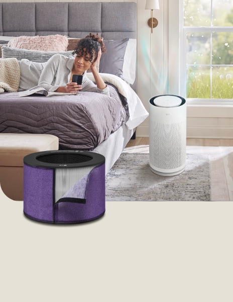 Purificador de aire LG con filtro antialérgico funcionando junto a una cama, mientras una mujer lee un libro cerca.	