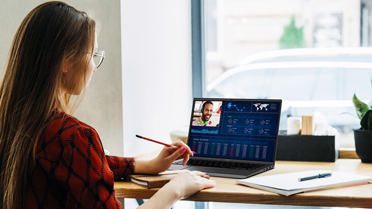 It shows an image of a woman sitting in front of a laptop and videoconferencing using a built-in webcam & speakers.