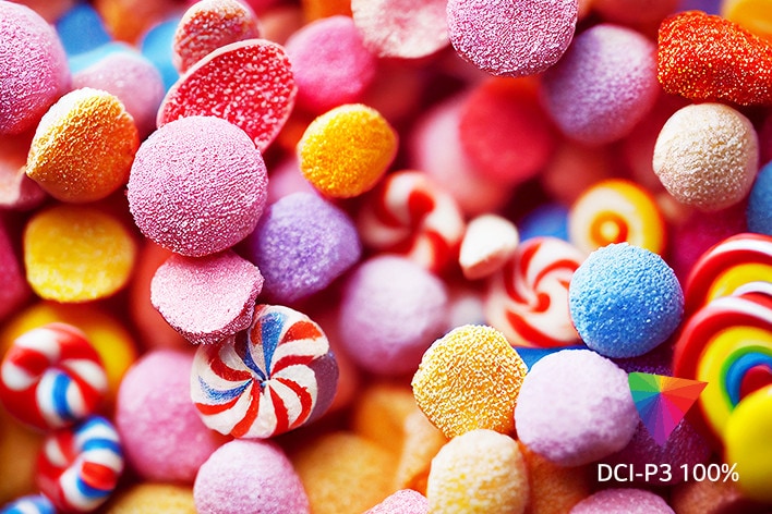 Close-up of vibrant, colorful candies with various textures and shapes, featuring the DCI-P3 100% logo in the corner.