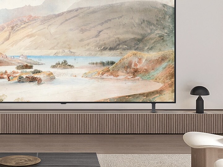 Close-up of a corner of an LG OLED TV in a living room. It is on a stand and it. Can be seen how the slim silhouette matches well with the interior design. 