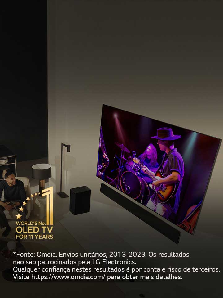 Uma perspetiva aérea de um homem e uma mulher a assistir a um concerto numa grande OLED TV num apartamento moderno. Aparece na imagem o emblema "A OLED TV número 1 do mundo há 11 anos". Uma declaração de isenção de responsabilidade diz o seguinte: “Fonte: Omdia. Envios unitários, 2013 a 2023. Os resultados não são patrocinados pela LG Electronics. Qualquer confiança nestes resultados é por conta e risco de terceiros. Visite https://www.omdia.com/ para obter mais detalhes.”
