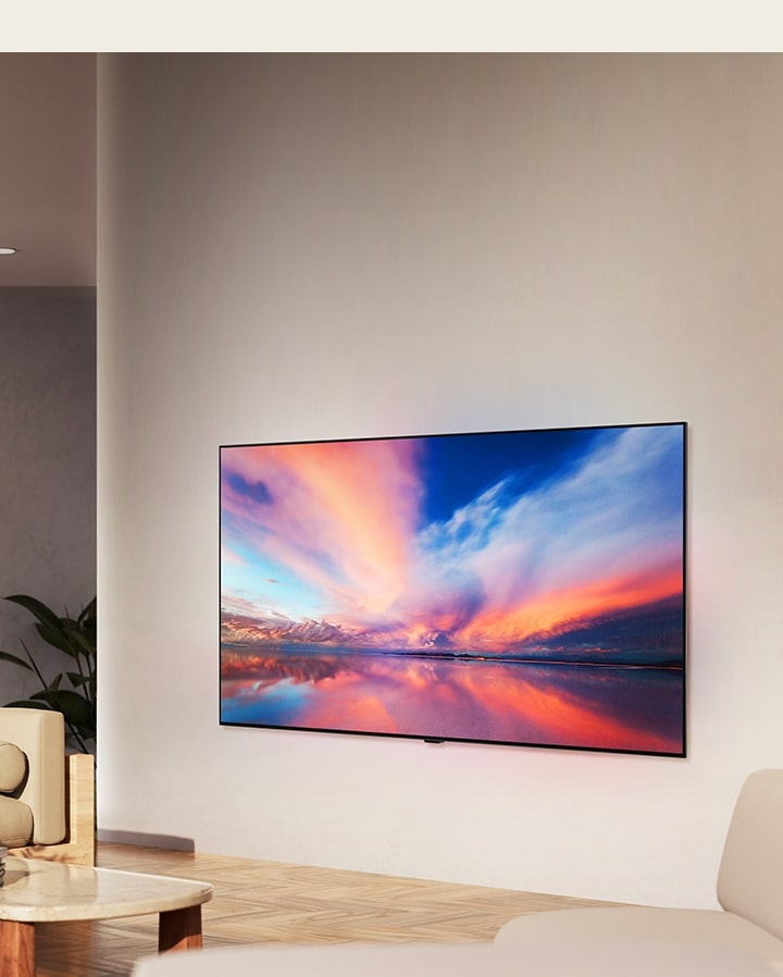 Uma imagem do LG OLED B4 na parede de uma sala de estar neutra, mostrando uma fotografia colorida de um pôr do sol sobre o oceano.