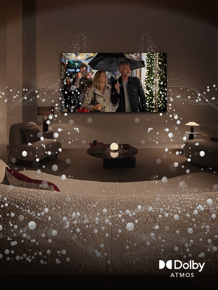 Uma imagem de uma sala de estar acolhedora e pouco iluminada. É exibida uma cena na televisão em que um casal está a usar um guarda-chuva e gráficos circulares brilhantes rodeiam a sala. Logótipo Dolby atmos no canto inferior esquerdo.