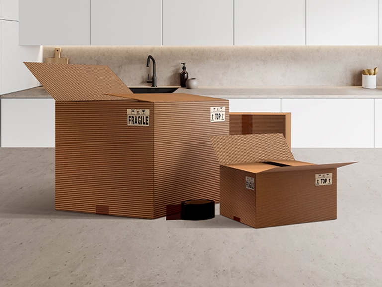 Caixas de embalagem com a etiqueta “FRÁGIL” numa cozinha moderna, mostrando peças e acessórios para a instalação de uma máquina de lavar loiça LG.