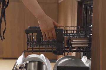 Pessoa a levantar o cesto de loiça da máquina LG para criar mais espaço por baixo, para depois colocar no cesto inferior itens grandes como panelas.
