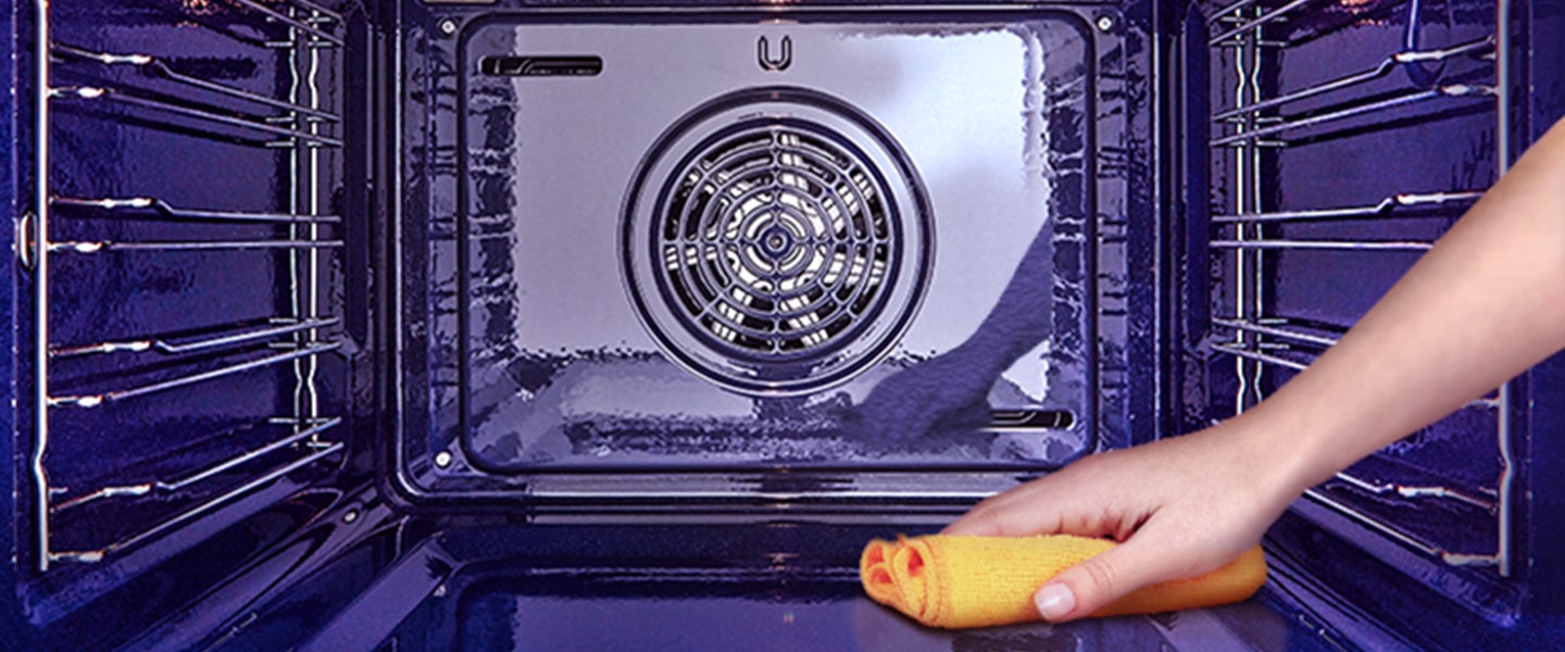 Imagem de um forno a ser limpo por dentro com um pano.