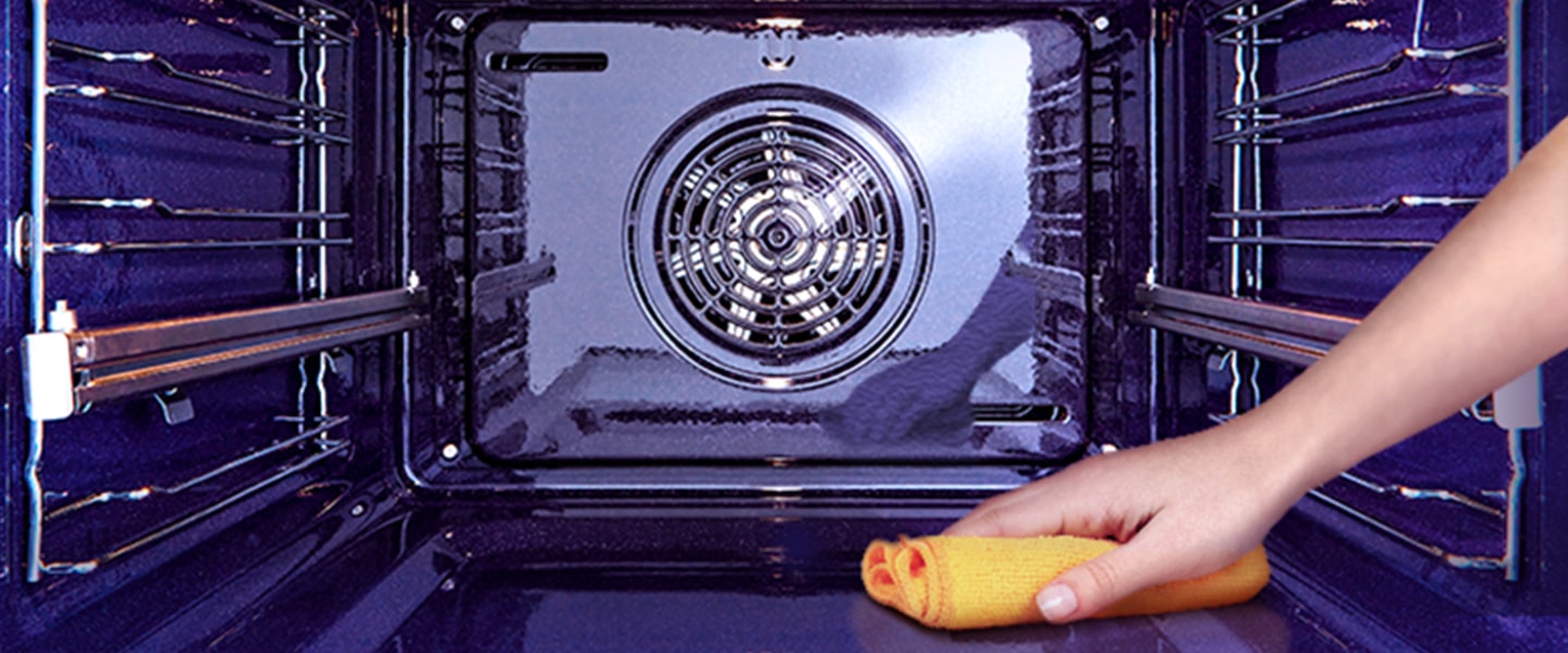 Imagem de um forno a ser limpo por dentro com um pano.