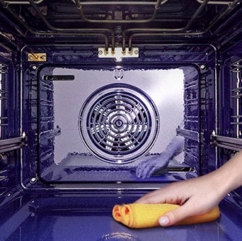 Imagem de uma pessoa a limpar o interior do forno com um pano.