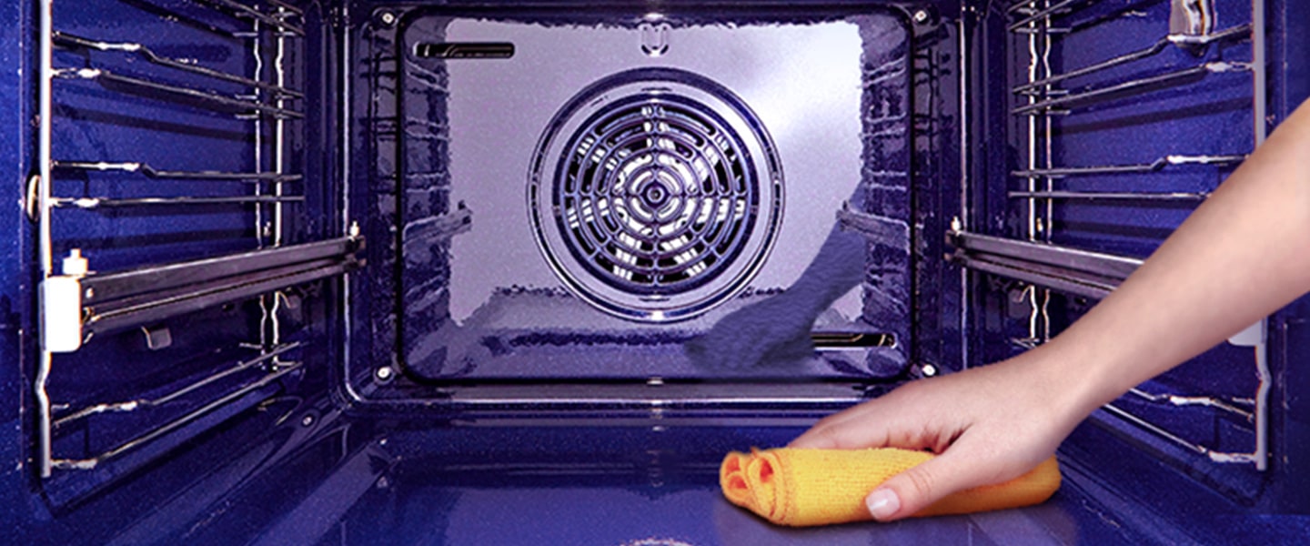 Imagem de um forno a ser limpo por dentro com um pano.