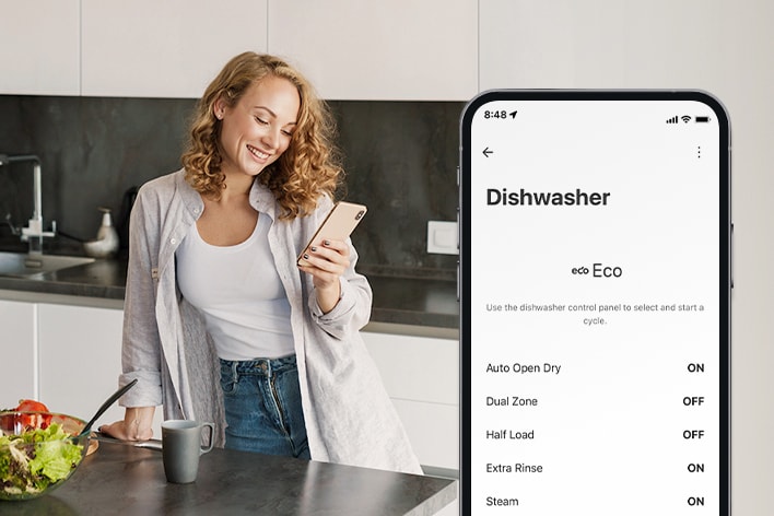 Mulher na cozinha a definir as suas preferências do ciclo de lavagem através da app LG ThinQ.