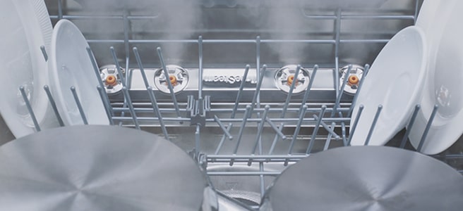 Filmagem em grande plano de vários tipos de pratos a serem lavados a vapor na máquina de lavar loiça.