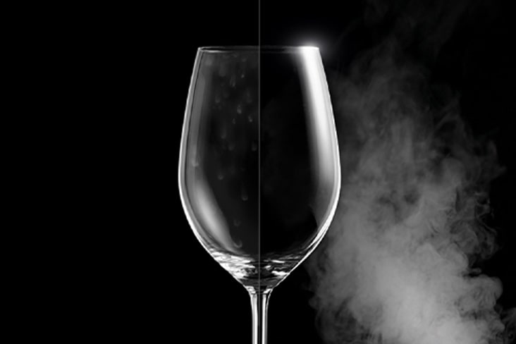 Um copo de vinho com manchas de água de um lado e cristalino do outro, mostrando a diferença após a lavagem a vapor.	