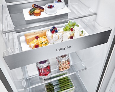 O interior do frigorífico mostra uma gaveta chamada de "Utility Box". Três setas indicam que a gaveta pode ser aberta para aceder aos alimentos que estão no interior.