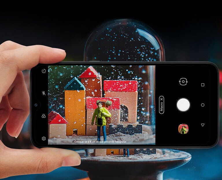Vista ampliada de alguém a segurar um smartphone e a tirar uma fotografia a uma bola de neve