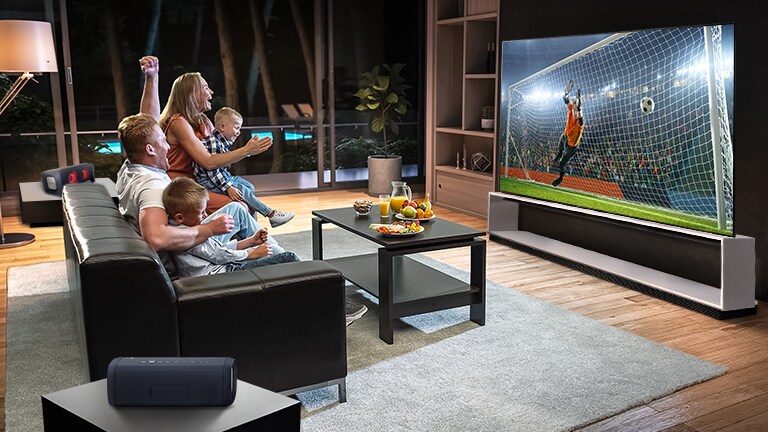 Uma família sentada num sofá a ver futebol na TV