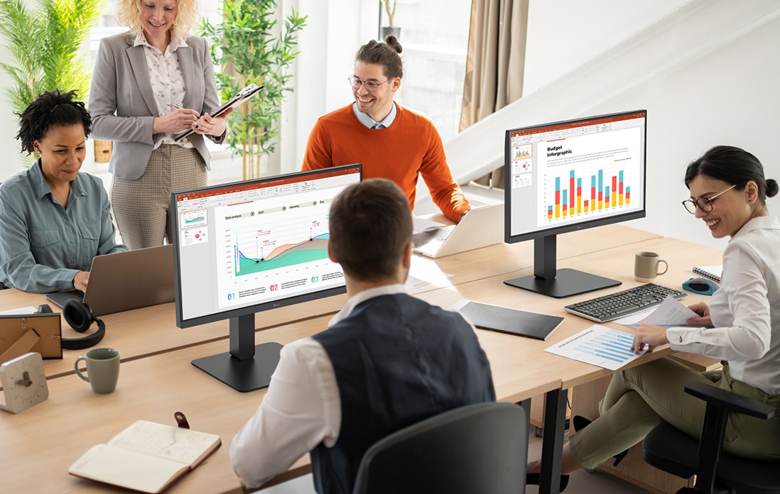 Colaboradores sentados em mesas de escritório e a conversar.