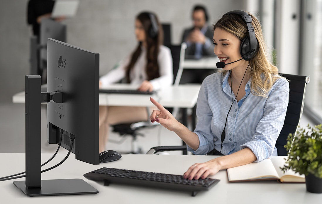 Uma mulher com auscultadores está a trabalhar enquanto olha para um monitor.