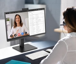 Uma mulher com auscultadores está a fazer uma videoconferência com a câmara Web incorporada.