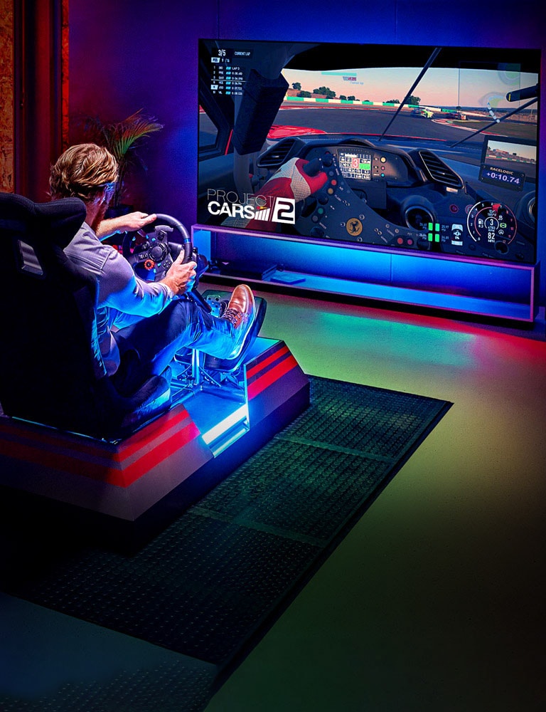 Um homem sentado numa cadeira de corrida à frente de uma TV OLED da LG grande a jogar num jogo de corridas (desloque-se para baixo na página)