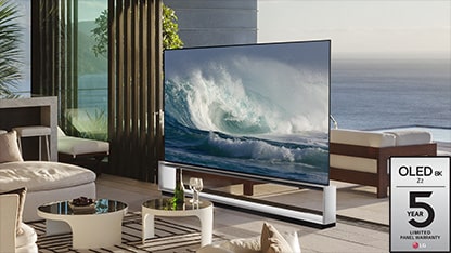 A LG OLED Z2 está em uma sala minimalista branca, na frente de uma janela com vista para um bosque com árvores.