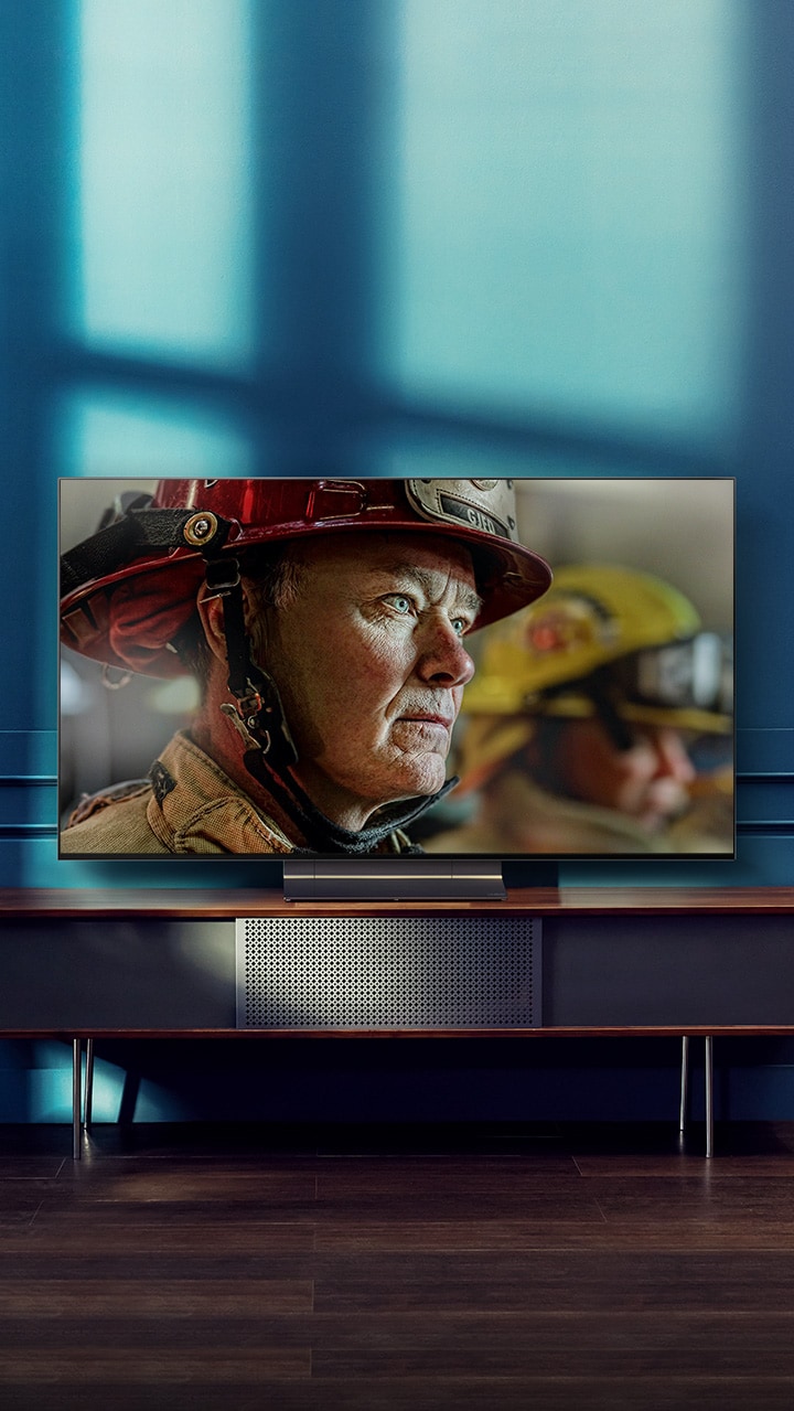 Uma TV OLED da LG montada na parede numa sala branca e brilhante com decorações naturais. Conforme o ecrã se move, a cena muda do dia para a noite.