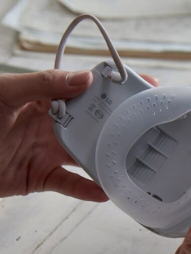 أيدي تمسك بالقناع تظهر الجزء الداخلي شرائط الأذن. 