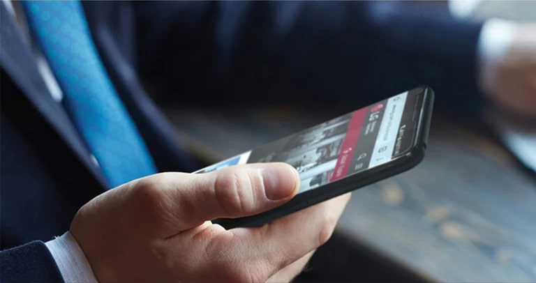 صورة لرجل يحمل هاتفًا ذكيًا مع صفحة ويب LG على الشاشة. 