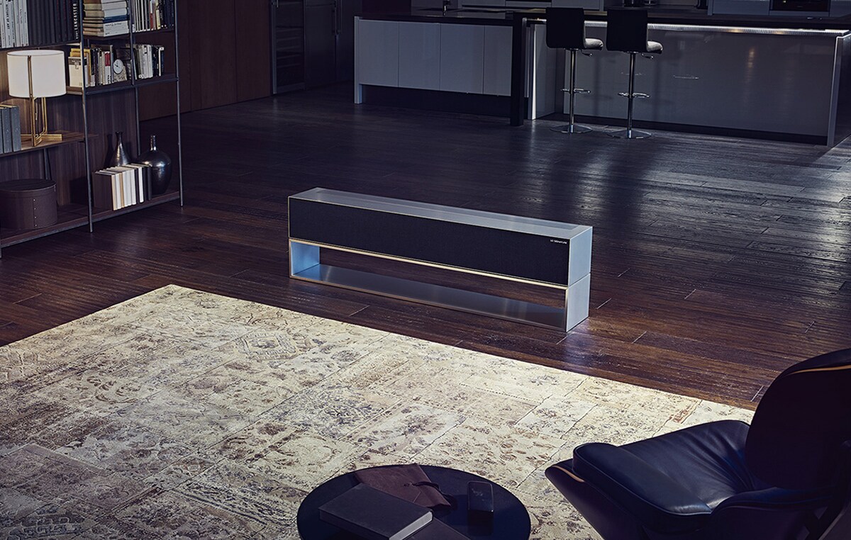 مشهد عريض للمطبخ وغرفة المعيشة في وجود تلفزيون LG SIGNATURE Rollable OLED في وضع الشاشة المخفية.
