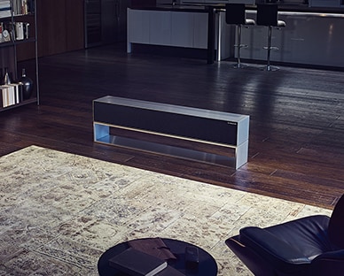  مشهد عريض للمطبخ وغرفة المعيشة في وجود تلفزيون LG SIGNATURE Rollable OLED في وضع الشاشة المخفية.