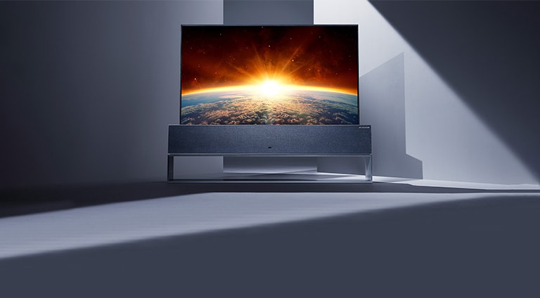 صورة لتلفزيون LG SIGNATURE Rollable في وضع الشاشة الكاملة موضوعًا في وسط غرفة رمادية.