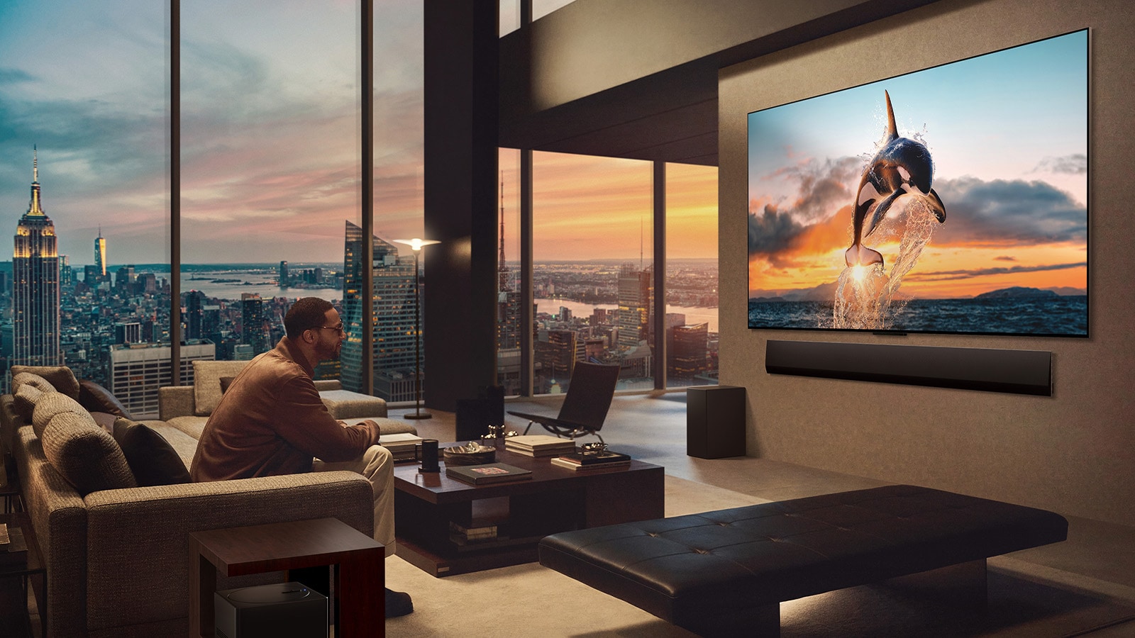 غرفة معيشة واسعة مع إطلالة على أفق المدينة. تلفزيون LG OLED TV مثبت على الحائط مع مكبر صوت LG Soundbar. يسمح التصميم One Wall Design بتركيب التلفزيون على الحائط ومزجه بشكل جيد مع المساحة. صندوق Zero Connect Box مرئي، ولكنه مخفي في الوقت نفسه.